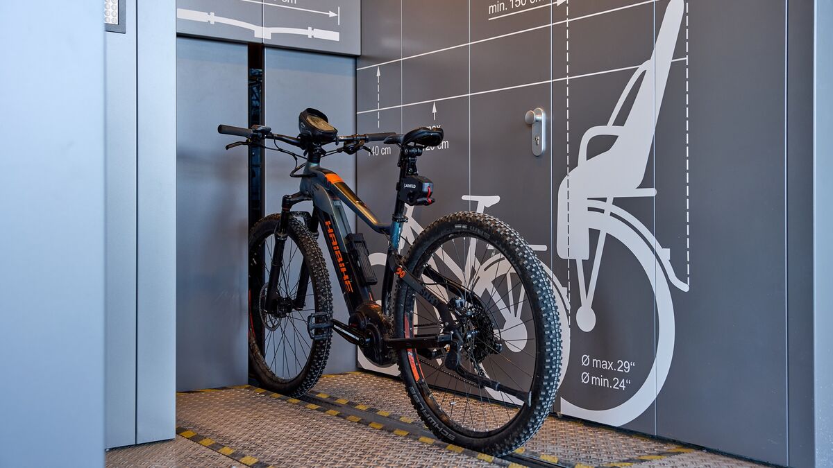 Un vélo sur un rail devant un système de stationnement automatique pour vélos