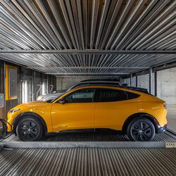 De afbeelding toont een auto op een platform binnen een geautomatiseerd parkeersysteem in een moderne ondergrondse parkeergarage.