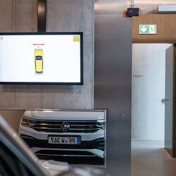 The car is positioned in front of a mirror and a monitor