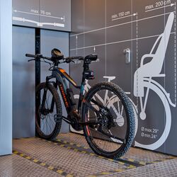 Un vélo sur un rail devant un système de stationnement automatique pour vélos