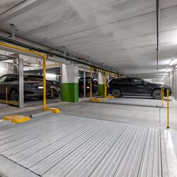 Plusieurs voitures sont stationnées sur la plateforme de stationnement dans un parking souterrain.