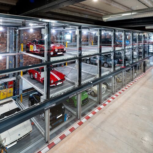 Vue en perspective du système de stationnement du Motorworld de Majorque, avec des voitures de sport exposées dans des vitrines