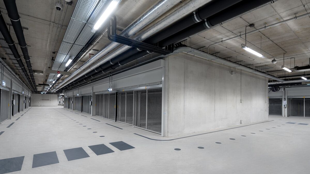 Parking souterrain moderne avec zone de croisement, voies de circulation continues et systèmes de stationnement disposés de part et d’autre.