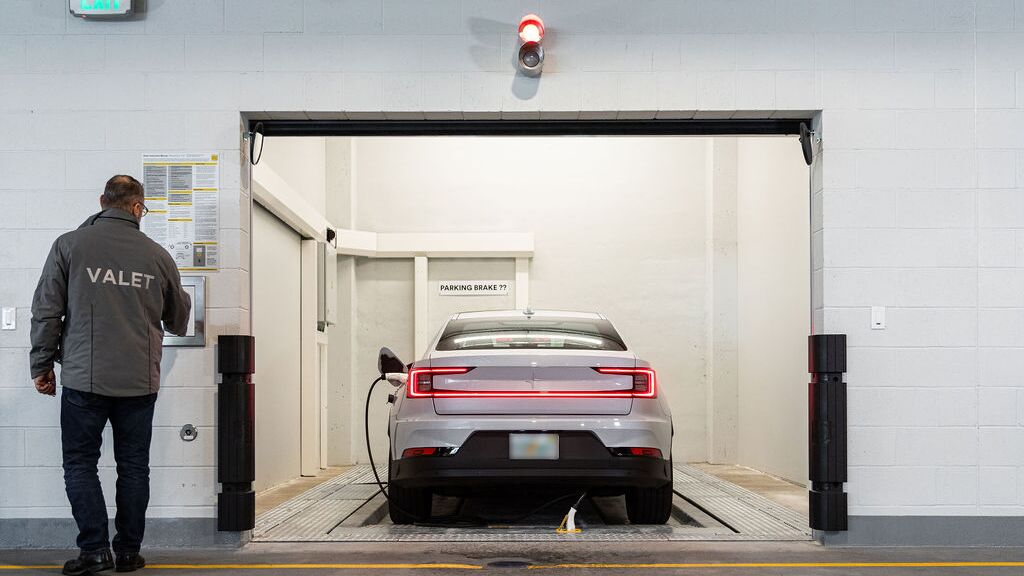 De afbeelding toont de overdrachtsruimte van een geautomatiseerd parkeersysteem, waar de bestuurder het parkeerproces start zodat het voertuig automatisch naar het parkeersysteem wordt verplaatst en geparkeerd.