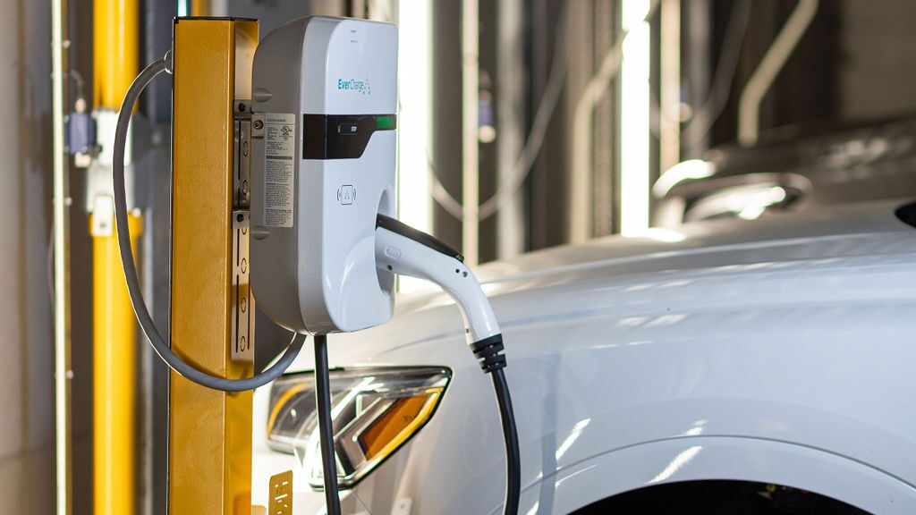 Un véhicule est stationné sur la plateforme d’un système de stationnement et est rechargé grâce à l’installation de recharge intégrée pour véhicules électriques.