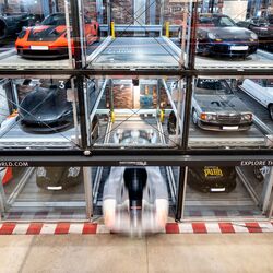 Un système de stationnement comprenant plusieurs voitures, soigneusement alignées contre un mur du musée