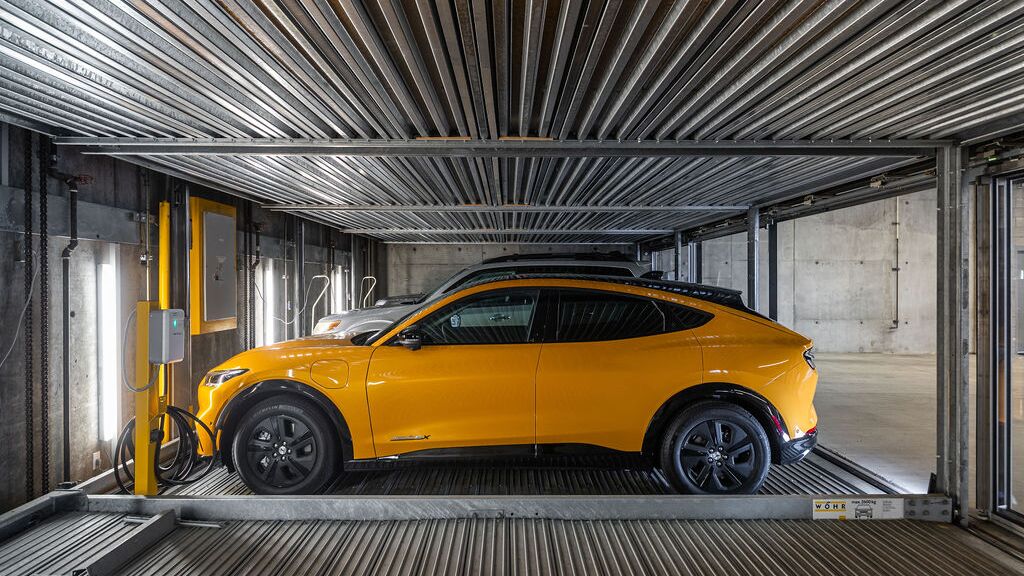 De afbeelding toont een auto op een platform binnen een geautomatiseerd parkeersysteem in een moderne ondergrondse parkeergarage.