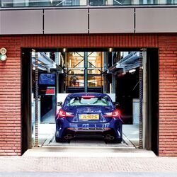 House wall with an open garage door into which a car is driving