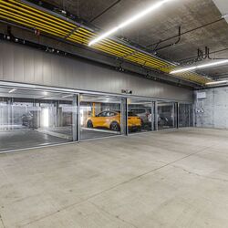 De afbeelding toont een moderne ondergrondse parkeergarage met meerdere glazen parkeerplaatsen van een parkeersysteem.