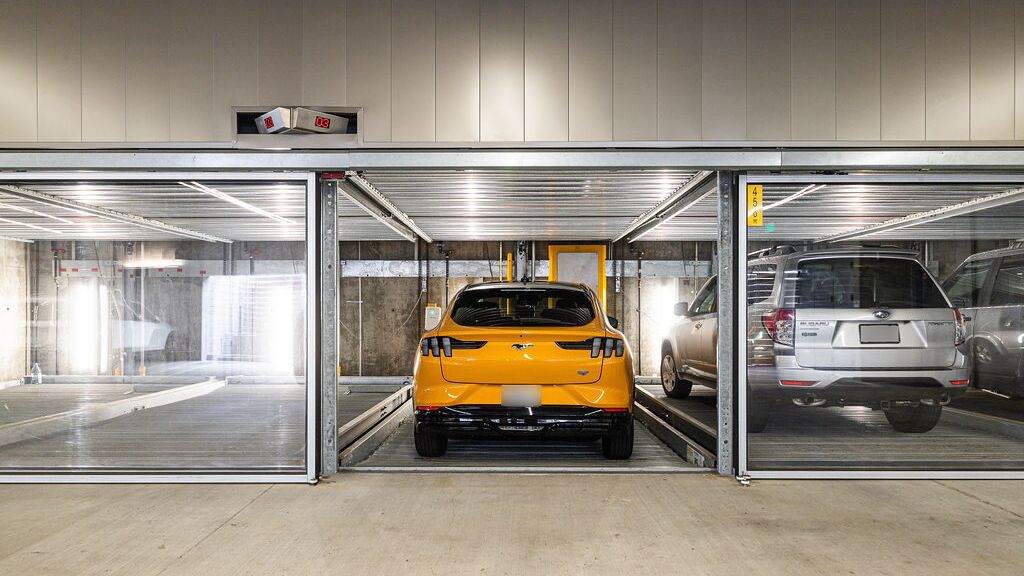 De afbeelding toont een moderne ondergrondse parkeergarage met meerdere glazen parkeerplaatsen van een parkeersysteem.