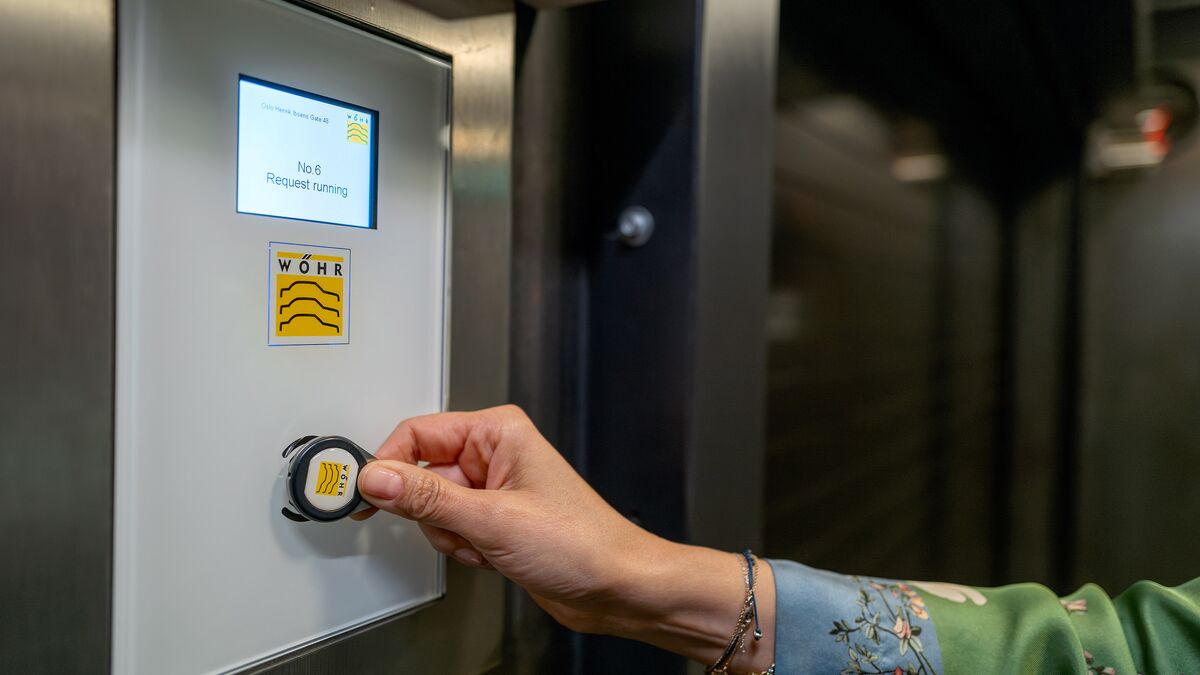 Une femme présente une puce RFID devant le capteur d'un panneau de commande