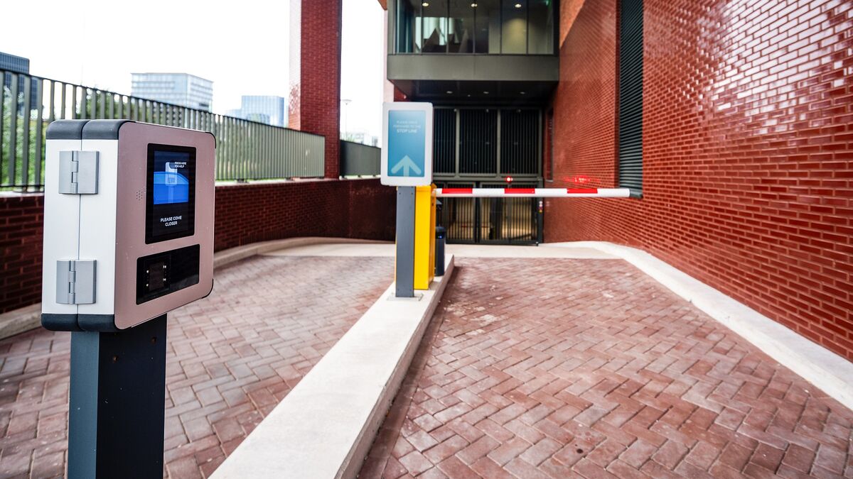 Entrée d’un système de stationnement moderne avec terminal d’accès, système de guidage numérique et barrière automatique.
