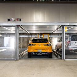 De afbeelding toont een moderne ondergrondse parkeergarage met meerdere glazen parkeerplaatsen van een parkeersysteem.