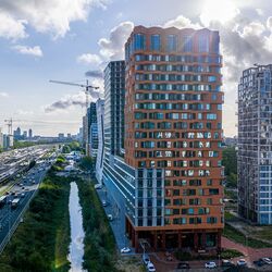 Quartier urbain moderne avec des immeubles de grande hauteur, des espaces verts et de bonnes infrastructures.