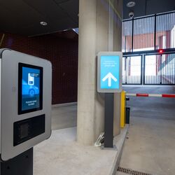 Sortie d’un système de stationnement moderne avec terminal d’accès, système d’information numérique pour les conducteurs et barrière automatique.