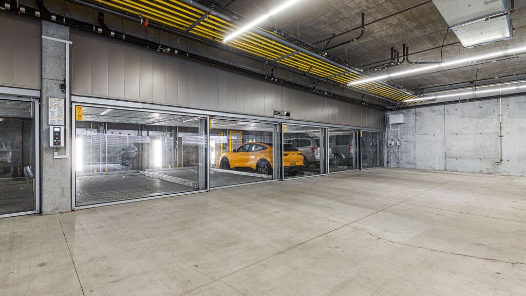 De afbeelding toont een moderne ondergrondse parkeergarage met meerdere glazen parkeerplaatsen van een parkeersysteem.