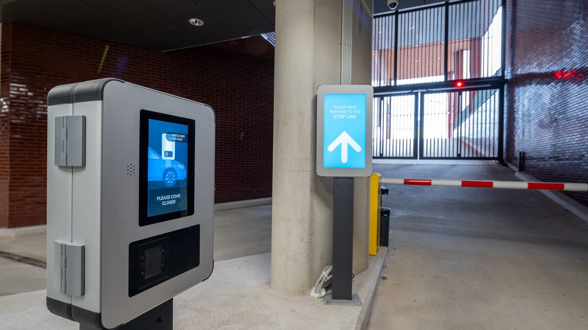 Sortie d’un système de stationnement moderne avec terminal d’accès, système d’information numérique pour les conducteurs et barrière automatique.